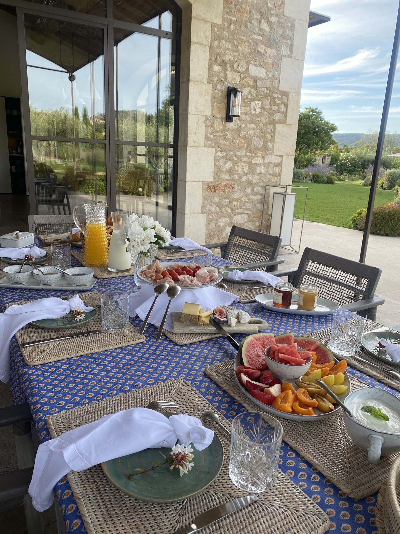 Petit-déjeuner en terrasse nappe bleue avec fruits frais et fromages